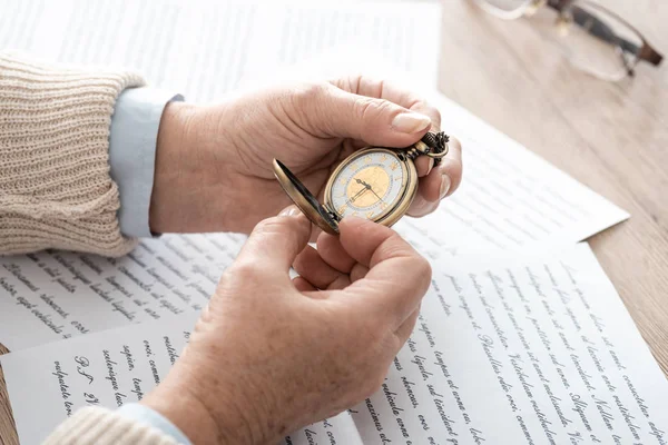 Cropped view of senior man holding pocket watch near papers with letters — Stock Photo