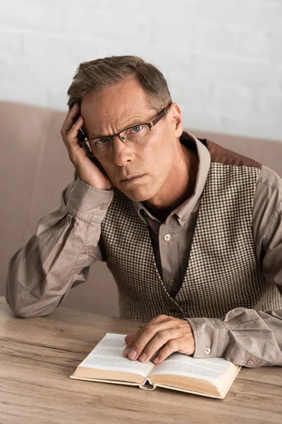 Sad senior man with memory loss sitting near book — Stock Photo