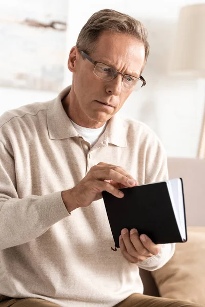 Homem idoso com doença de alzheimer segurando notebook em casa — Fotografia de Stock
