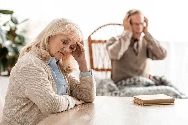 Selective focus of upset retired woman sitting near husband with mental illness — Stock Photo