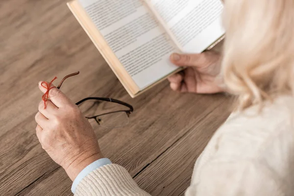 Cropped view of senior woman with alzheimers disease string human finger reminder  reading book wile holding glasses — Stock Photo