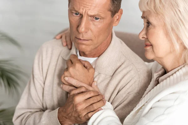 Traurige Rentnerin umarmt Ehemann mit Alzheimer-Erkrankung zu Hause — Stockfoto