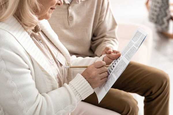 Cropped view of senior man sitting with wife solving crossword — Stock Photo