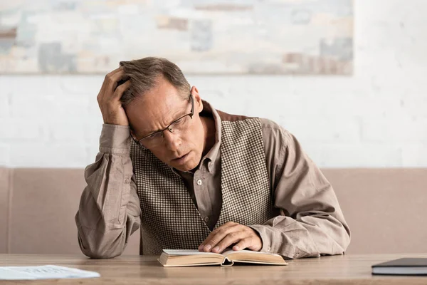 Senior man with dyslexia reading book at home — Stock Photo