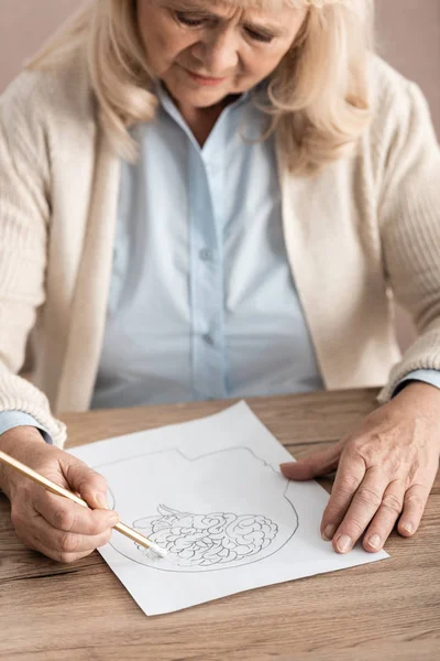 Selective focus of sick senior woman drawing on paper — Stock Photo