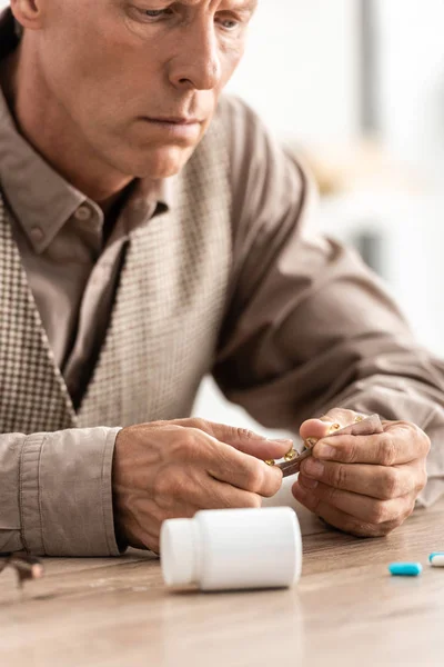 Cropped view of sick senior man looking at pills — Stock Photo