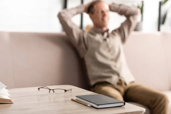 Selective focus of table with glasses and notebook near senior man — Stock Photo