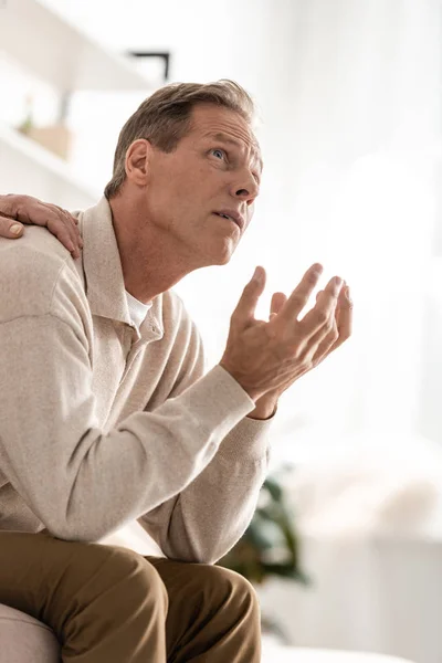 Ausgeschnittene Ansicht einer Seniorin, die die Schulter ihres kranken Mannes berührt, der zu Hause sitzt — Stockfoto