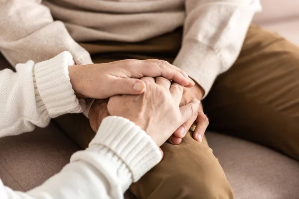 Vista recortada del hombre y la mujer mayores tomados de la mano - foto de stock