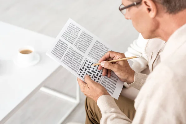 Selektiver Fokus eines älteren Mannes mit Legasthenie, der Bleistift und Kreuzworträtsel hält — Stockfoto