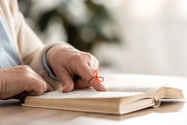 Vista recortada de la mujer mayor con alzheimers enfermedad cadena dedo humano recordatorio cerca del libro - foto de stock