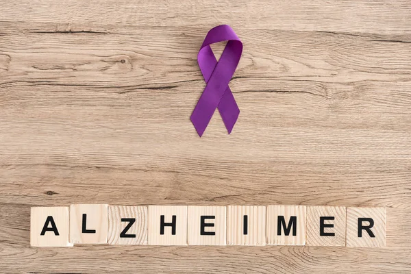 Top view of purple ribbon near wooden cubes with alzheimer letters — Stock Photo
