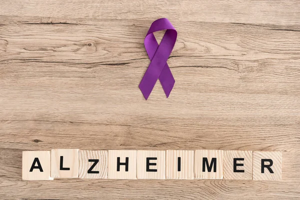 Vista superior de la cinta púrpura cerca de cubos de madera con letras de alzheimer - foto de stock