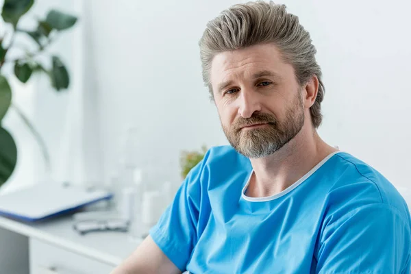 Handsome patient in medical gown looking away in hospital — Stock Photo