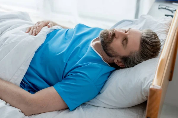 Vista de ángulo alto del paciente en bata médica durmiendo en el hospital - foto de stock