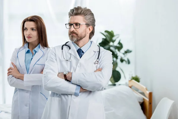 Médecins en blouse blanche avec les bras croisés regardant loin à l'hôpital — Photo de stock