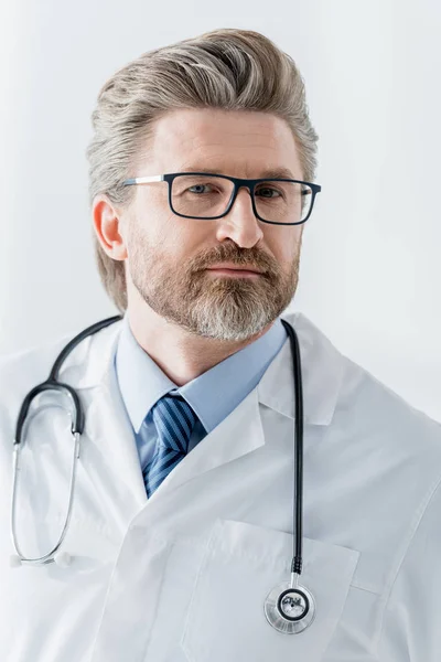 Guapo doctor en blanco abrigo mirando cámara en hospital - foto de stock