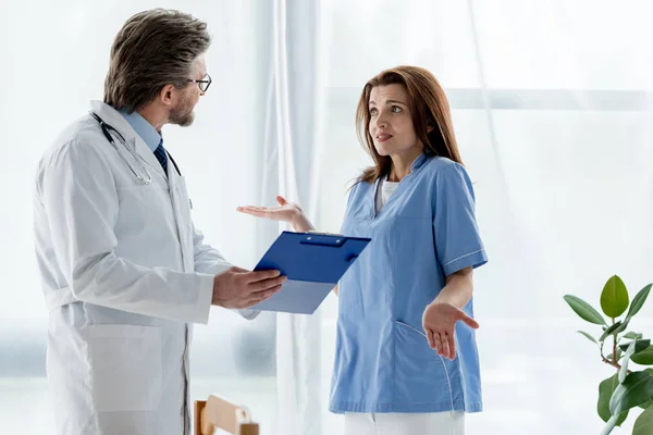 Médecin en manteau blanc parlant avec infirmière choquée à l'hôpital — Photo de stock