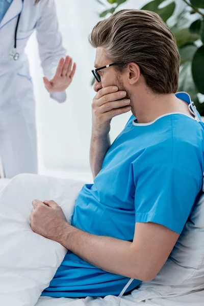 Cropped view of doctor in white coat calming down sad patient in hospital — Stock Photo