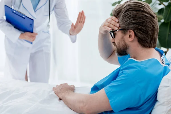 Ausgeschnittener Blick auf Arzt im weißen Kittel beruhigt traurigen Patienten im Krankenhaus — Stockfoto