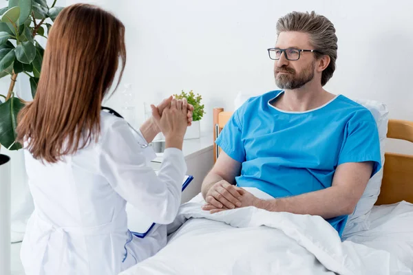 Вид ззаду лікаря в білому пальто, що розмовляє з пацієнтом в лікарні — стокове фото