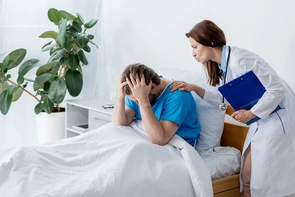 Médico de bata blanca calmando paciente molesto en el hospital - foto de stock