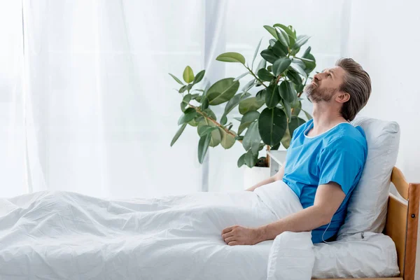 Seitenansicht einer Patientin im Arztkittel, die im Krankenhaus nach oben blickt — Stockfoto