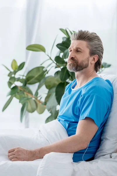 Handsome patient in medical gown looking away in hospital — Stock Photo