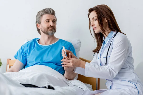 Doctor in white coat taking blood test from patient in hospital — Stock Photo