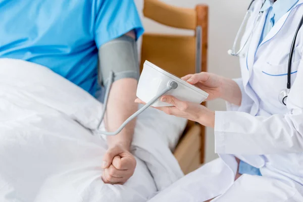 Ausgeschnittene Ansicht eines Arztes, der den Blutdruck des Patienten im Krankenhaus misst — Stockfoto