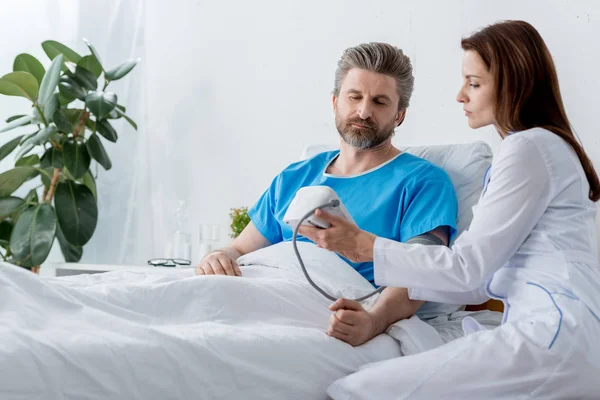 Arzt im weißen Kittel misst Blutdruck des Patienten im Krankenhaus — Stockfoto