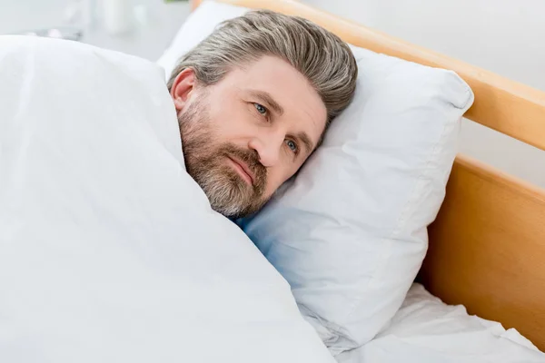 Vue grand angle du patient en robe médicale couché dans le lit — Photo de stock