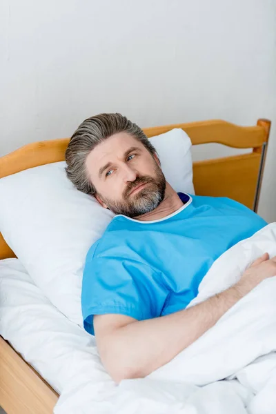 Visão de alto ângulo do paciente em vestido médico deitado e olhando para longe no hospital — Fotografia de Stock