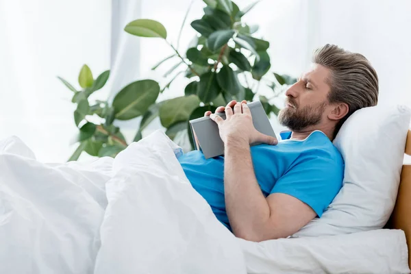 Patient in medical gown sleeping with book in hospital — Stock Photo