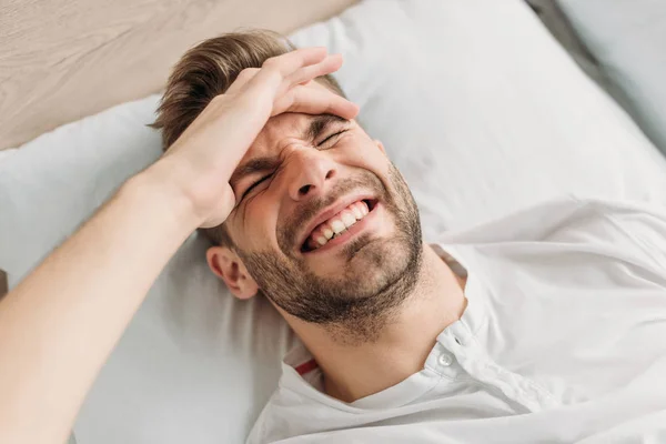 Vista aérea del joven tocando la cabeza mientras sufre de migraña - foto de stock