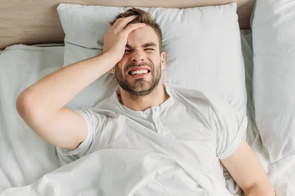 Top view of young man touching head while suffering from migraine — Stock Photo