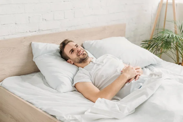 Joven acostado en la cama y sufriendo de dolor abdominal - foto de stock