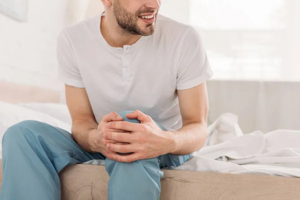 Cropped view of young man touching knee while suffering from pain — Stock Photo