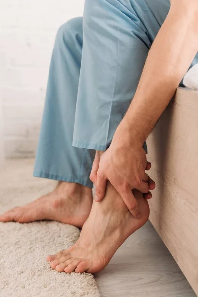 Cropped view of man touching leg while suffering from pain in Achilles tendon — Stock Photo