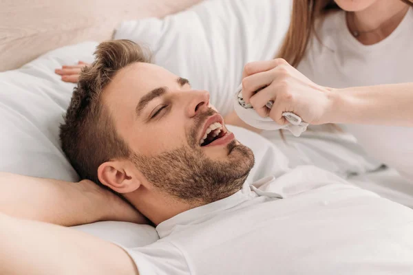 Cropped view of woman holding hanky near face of snoring husband — Stock Photo