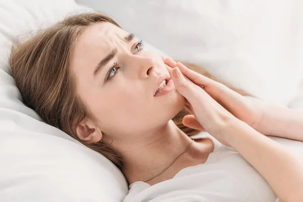 Sconvolto ragazza toccando guancia mentre soffre di mal di denti — Foto stock