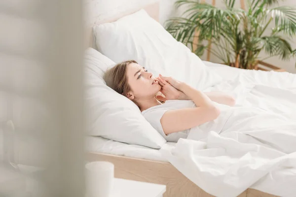 Selektiver Fokus einer jungen Frau, die im Bett liegt und unter Zahnschmerzen leidet — Stockfoto