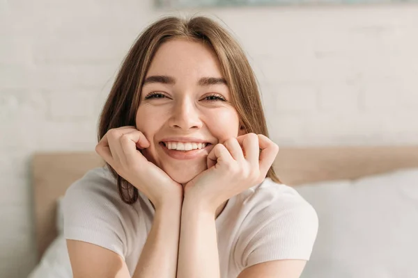 Joyeuse jeune femme riant à la caméra tout en se tenant la main près du visage — Photo de stock