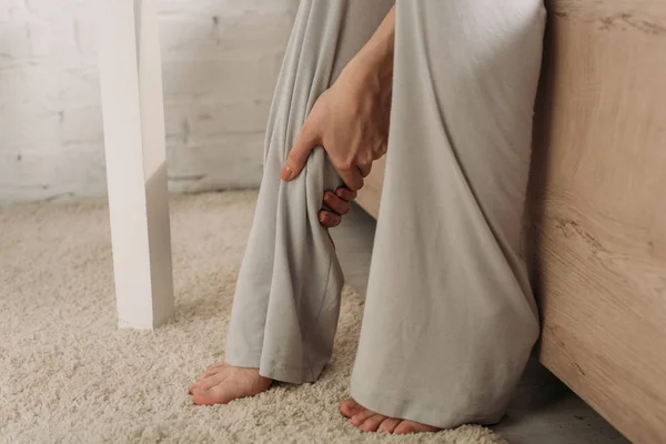 Visão cortada da mulher tocando a perna enquanto sofre de dor — Fotografia de Stock