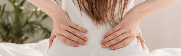 Cropped view of girl touching loin while suffering from pain, panoramic shot — Stock Photo