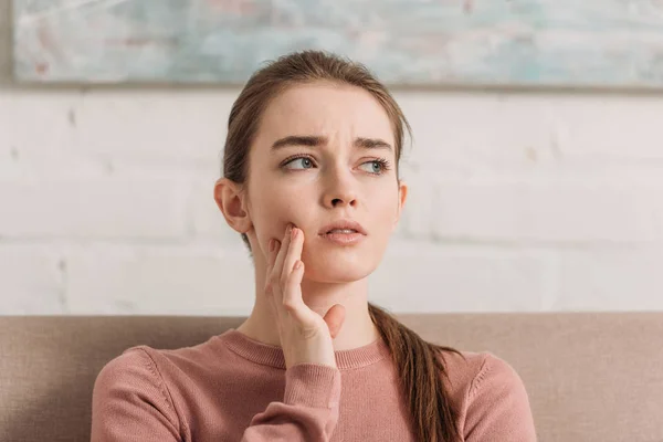 Frowned girl looking away while suffering from toothache — Stock Photo