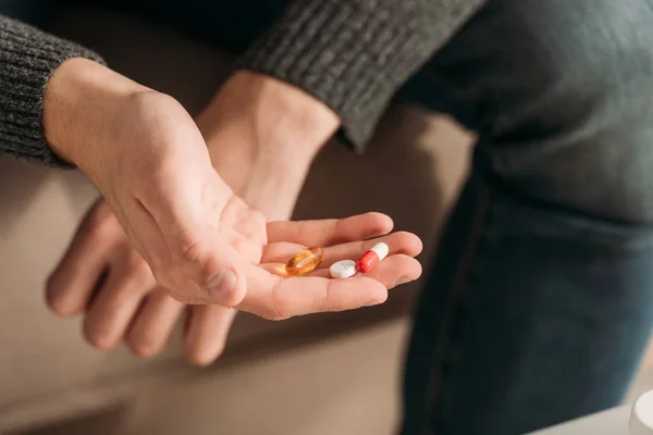 Cropped view of sick man with handfull of pills — Stock Photo
