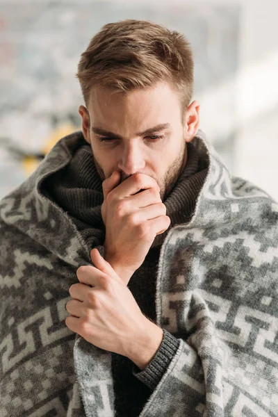 Sick man, wrapped in blanket, coughing while covering mouth with hand — Stock Photo