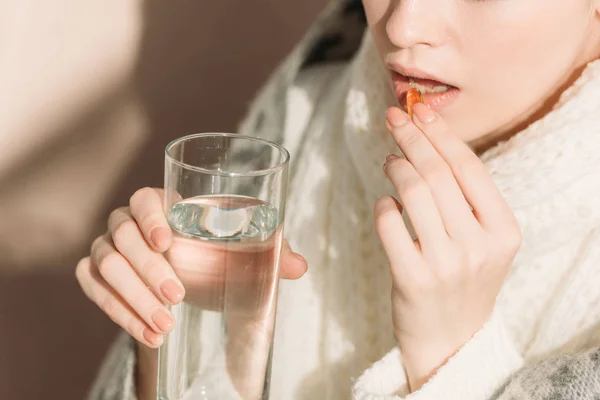 Vue recadrée de la femme malade tenant un verre d'eau tout en prenant des médicaments — Photo de stock