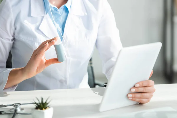 Vista ritagliata del medico che mostra pillole al paziente sulla consultazione online sul tablet digitale in ufficio — Foto stock